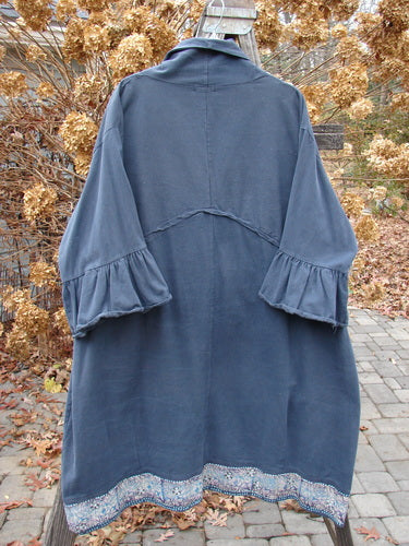 A Barclay Decora Brushed Twill Flutter Coat in Navy, size 2. A swingy, ruffled coat made from heavy brushed cotton twill. Features include a deep V neckline, matching buttons, and flutter sleeves. With giant round pockets and a paneled hemline, this coat is painted in a tiny garden theme. Bust: 60, Waist: 60, Hips: 62, Sweep: 75, Length: 46 inches.