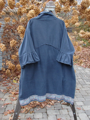 A Barclay Decora Brushed Twill Flutter Coat in Navy, size 2. A swingy, ruffled coat made from heavy brushed cotton twill. Features include a deep V neckline, dark matching buttons, and flutter sleeves. With giant round pockets and a paneled, widening hemline, this coat is painted in a tiny garden theme. Bust: 60, Waist: 60, Hips: 62, Sweep: 75, Lower Bell: 80, Length: 46 inches.
