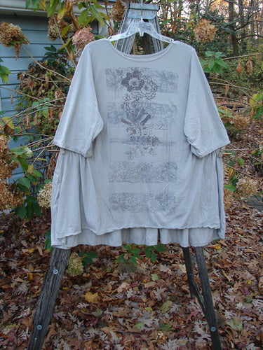 Barclay Three Quarter Sleeve Side Gather Sweep Tunic Bouquet Natural Size 2 displayed on a wooden rack, highlighting its lightweight, pocketless design, perfect for expressing individuality through vintage-inspired fashion.