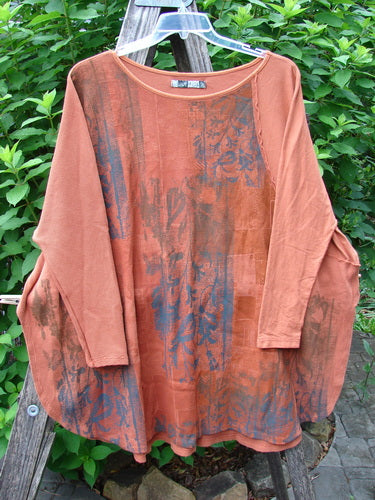 Barclay Thermal Monte Verde Vented Tunic Harvest Autumn OSFA displayed on a wooden pole, showcasing its rounded neckline, widening lower shape, side vents, and blended botanical theme against a vintage backdrop.