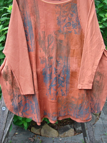 Barclay Thermal Monte Verde Vented Tunic Harvest Autumn OSFA displayed on a fence, showcasing its rounded neckline, side vents, and exterior stitchery, crafted from medium-weight organic cotton with botanical theme paint.