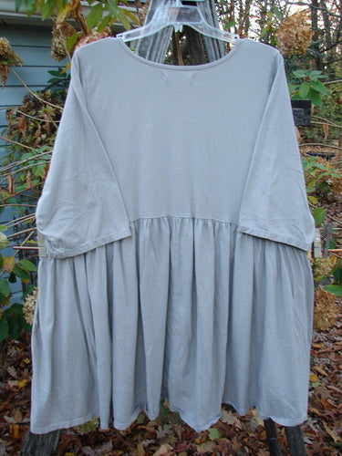 Barclay Three Quarter Sleeve Side Gather Sweep Tunic Bouquet Natural Size 2 displayed on a clothes rack, highlighting its lightweight, pocketless design and elegant, gathered sweep, embodying Bluefishfinder.com's vintage, creative style.