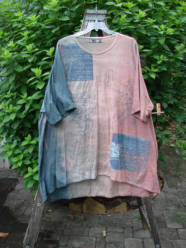 Barclay Art Tee Bicycle Floral Basket in Mottled Mauve Gray, showcasing a longer tunic length, drop shoulders, loose three-quarter sleeves, and rounded neckline, captured on a hanger outdoors amidst greenery.