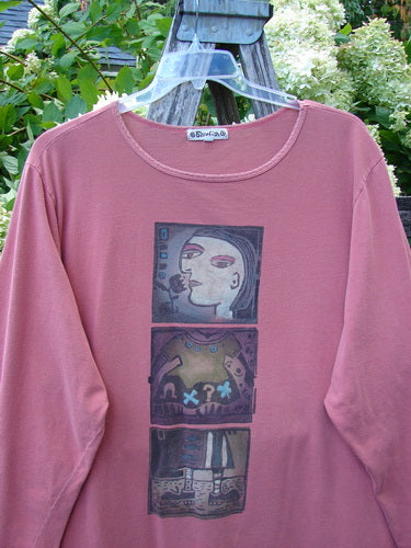 Barclay Long Sleeved Tee Studio Tee Triple Modernist Apricot Size 3, a dusty apricot long-sleeve shirt with a wide crew neckline and three stacked graphic panels centered on the chest. The soft knit hangs from a clear hanger, with leafy greenery and weathered wood behind it.
