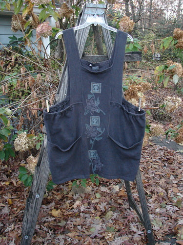 1995 Reprocessed Cottage Jumper Floral Vine Granite Size 3 displayed on a wooden ladder, showcasing its dense knit fabric, floral vine pattern, thick shoulder straps, and oversized front pockets.