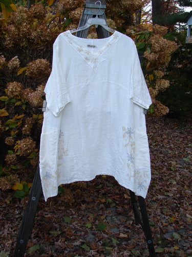 Barclay Linen Cross Over Dress with Daisy Theme, featuring V Neckline and Drop Shoulders, on a clothes swinger.