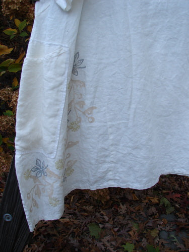 Barclay Linen Cross Over Dress with floral design, button detail, and leaves on the ground.