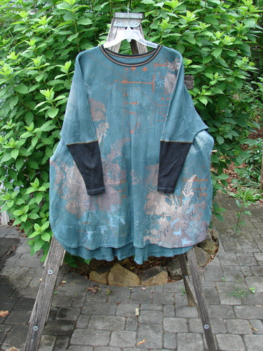 Barclay Thermal Contrast Revival Top Field Lightening Mottled Green Teal OSFA displayed on a clothes rack, showcasing black ribbed sleeves and a unique rounded neckline design.