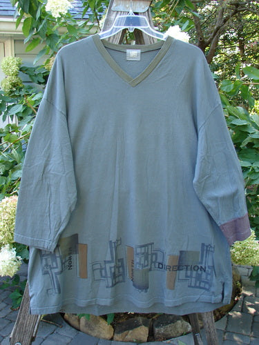 2000 V Neck Grid Top Directional Iron Size 2 displayed on a clothes rack, showcasing unique painted patterns, single cuff, V neckline, A-line shape, vented sides, rounded bottom sweep, and Blue Fish patch.