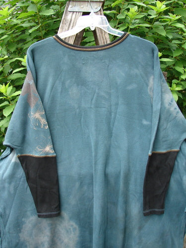 Barclay Thermal Contrast Revival Top in Mottled Green Teal OSFA with ribbed sleeves and neckline, showcasing a unique field lightning theme. Displayed on a clothes rack, highlighting its A-line shape and side vents.