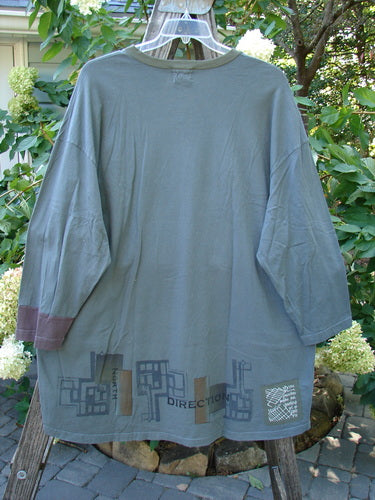 2000 V Neck Grid Top Directional Iron Size 2, long-sleeved shirt hanging on a tree, showcasing its unique painted design and V neckline, with visible contrasting single cuff and slightly rounded bottom sweep.