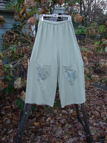 2001 Wishpocket Pant Airplane Kelp Size 1 displayed on a rack, featuring wide lowers, exterior knee pockets, and a cropped length, highlighting the unique airplane-themed design and elastic waistline.