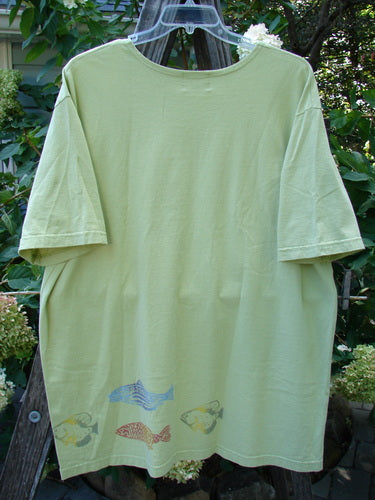 2000 Short Sleeved Tee Fish School Key Lime Pie Size 2, featuring drop shoulders, wider cut sleeves, and a fish school pattern, displayed on a clothesline.