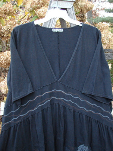 Black dress with V neckline, banded waist, flaring lower, and scallop hemline. Short sleeves with sea life theme.
