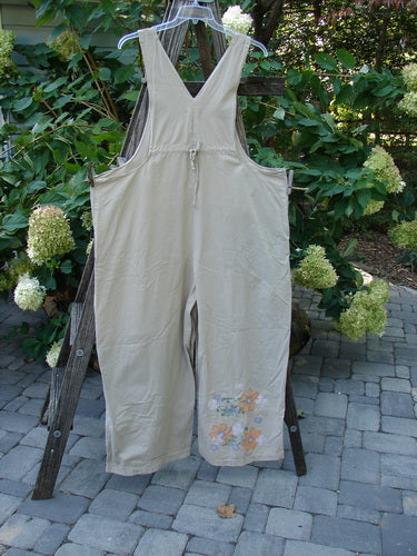 2000 Parachute Overall Pant Jumper Floral Dove Size 2 displayed on a wooden rack, showcasing adjustable shoulder straps, painted front bib pocket, and floral-themed wide lowers.