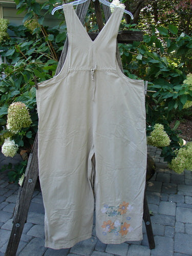 2000 Parachute Overall Pant Jumper Floral Dove Size 2 hanging on a clothesline, showcasing its lightweight cotton fabric, painted floral details, and sturdy adjustable straps.