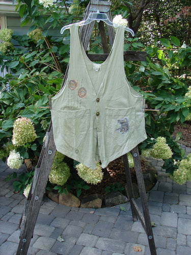 2001 Katy Vest Circle Rain Kelp Size 1 displayed on a wooden ladder. The vest features thinner shoulder straps, a wider rounded A-line shape, two front triangular pockets, and textured Blue Fish button closures.