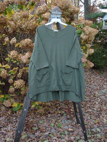 Barclay Hi Low Pocket Tunic Top on clothes rack, featuring rounded neckline, double lower front pockets, and longer three quarter length sleeves.