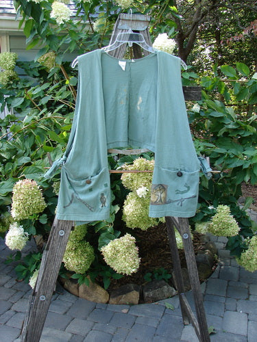 1994 Pocket Vest Magic Dance Kelp OSFA on a wooden rack, featuring a cropped back, two pockets with vintage buttons, and side ties for an adjustable fit.