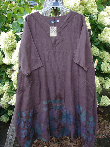 Barclay NWT Linen Cross Over Incense Dress in fig, size 0, shown on a hanger with a relaxed V-neck and elbow-length sleeves. The linen fabric has a matte, slightly textured finish, with a structural diamond floral print gathered along the hem in deep blue and black.
