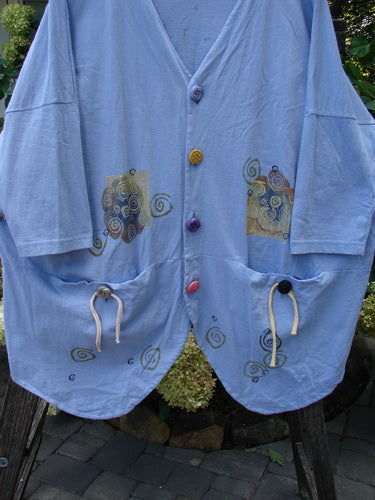 1997 Day Jacket Curl Wind Freesia OSFA with vintage buttons, dolman sleeves, V neckline, front drop pockets, rounded tails, and a scooped back hemline with draw cord and painted wind theme design.