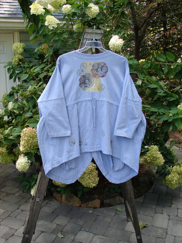 1997 Day Jacket Curl Wind Freesia OSFA displayed on a hanger, featuring vintage buttons, large front pockets, dolman sleeves, V neckline, rounded front tails, and a scooped back hemline with a draw cord.