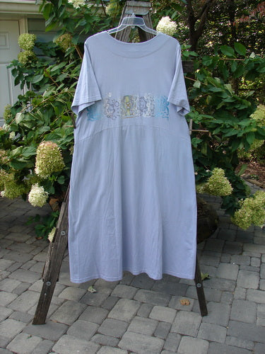 1999 Windmill Dress Turn Wind Lilac Size 2: A lilac dress with a sweeping A-line shape, squared double-paneled neckline, and flared hemline, hanging on a clothes rack.