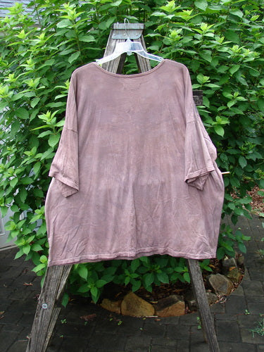 Barclay Center Seam Wide Line Tee Fern Fare Mottled Mauve OSFA displayed on a wooden stand swing, showcasing its wide boxy shape, drop shoulders, and central vertical seam in an outdoor setting.