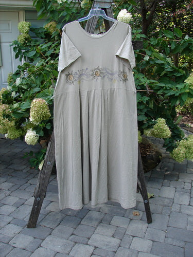 1997 Lawn Dress Star Path Wheat Size 2 on a rack, showcasing tailored pleats, a detachable apron with sectional pockets, and a drop waistline.