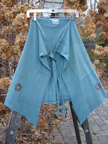 2000 NWT Grid Patch Wrap Skirt in Puddle, featuring a blue robe on a clothesline. Made from organic cotton, this skirt has a super long belt, cross-stitched accents, and a single huge stitched painted patch. Versatile and stylish, it can be worn as a mini skirt or over straight bottoms. Lengths: 27" and 23", Width: 56".