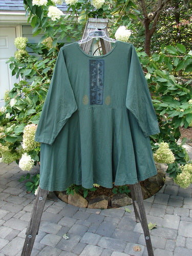 1994 Juniper Dress Forest Path Deep Moss Size 2 displayed on a wooden stand, showcasing a wider rounded collar, sectional panels, and a full sweeping swing lower.