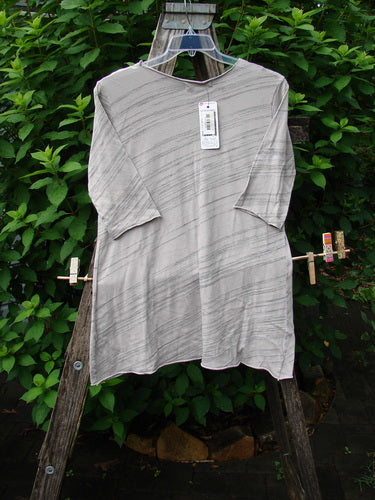 Barclay NWT Viscose Horizon Raw Cut Tee Wheat Field Vintage Quartz Striation Size 1 displayed on a wooden stand, showcasing its raw cut neckline and three-quarter sleeves in an A-line shape.