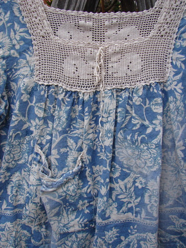 Magnolia Pearl Homespun Linen Crochet Bunny Blouse Tapestry Blue OSFA, showcasing a detailed blue and white floral pattern with a crochet square neckline and three-quarter length sleeves.