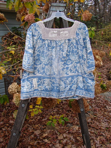 Magnolia Pearl Homespun Linen Crochet Bunny Blouse Tapestry Blue OSFA displayed on a swinger, showcasing its crochet square neckline, three-quarter sleeves, and front side drop pocket.