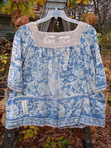 Magnolia Pearl Homespun Linen Crochet Bunny Blouse Tapestry Blue OSFA with a crochet square neckline, three-quarter sleeves, and a front pocket, displayed on a clothesline.