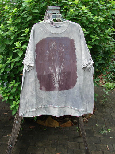 Barclay NWT Art Tee Floral Reach Raincloud Grey OSFA displayed on a hanger, showcasing its loose three-quarter sleeves, rounded neckline, and unique upward rounded front hem in a close-up view.