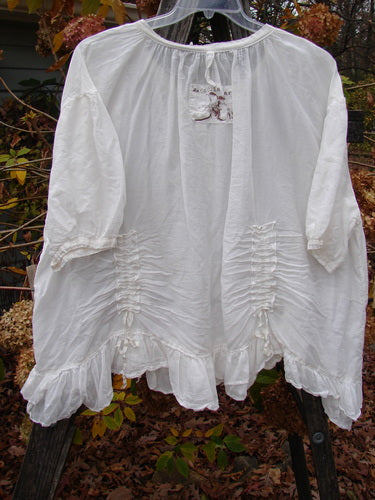 Magnolia Pearl Silk Voile Gather Drapery Top White OSFA on a rack, showcasing its ruffled hem, vertical gathers, and three-quarter sleeves, embodying the vintage style of BlueFishFinder.com.