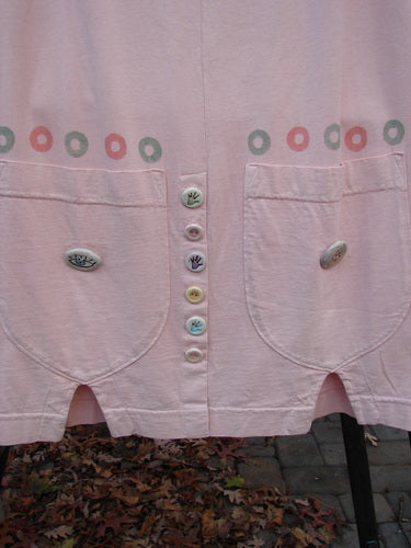 2001 Wishpocket Skirt Button Path Pink Tile Size 1: A close-up of a pink shirt with a 1/2 front drawstring waist, oversized lower rounded pockets, and polka dotted paint.