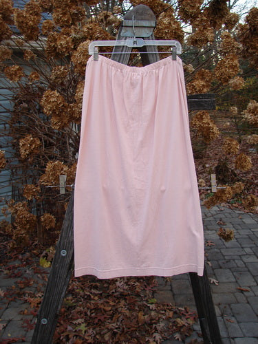 2001 Wishpocket Skirt Button Path Pink Tile Size 1: A pink skirt with a drawstring waist, oversized pockets, and ceramic buttons. Made from light organic cotton.