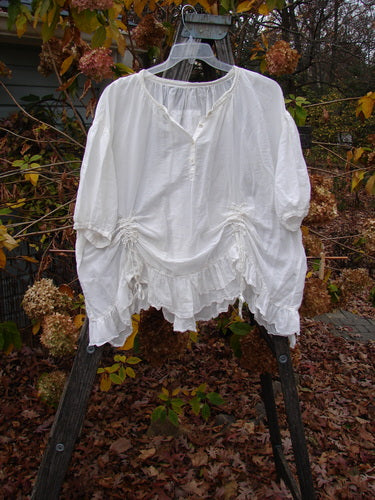 Magnolia Pearl Silk Voile Gather Drapery Top White OSFA displayed on a swing, showcasing its ruffled hem, three-quarter sleeves, and delicate button line, exemplifying Bluefishfinder.com's commitment to unique, expressive vintage fashion.