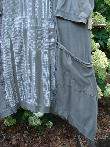 Barclay Raw Edge Flutter Drop Pocket Tunic in darkest sand, size 0, with a loose draped silhouette, raw-edged seams, and fluttering side panels. The soft, washed fabric shows a gray-toned body with vertical white stripe detailing and layered pocket trim.