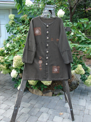 1997 Sample Spring Day Jacket Flower Pot Briquette Size 1 displayed on a wooden rack, featuring knotted buttons, yoked waistline, varying hem, and paneled sleeves with a sweeping swing skirt.