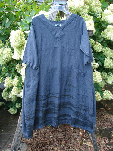 Barclay Linen Cross Over Incense Dress Structural Cliff in deep navy, size 0, hangs from a clear hanger in a relaxed A-line silhouette. The linen fabric has a softly crinkled texture, short sleeves, a crossover V-neck, and darker horizontal bands near the hem.