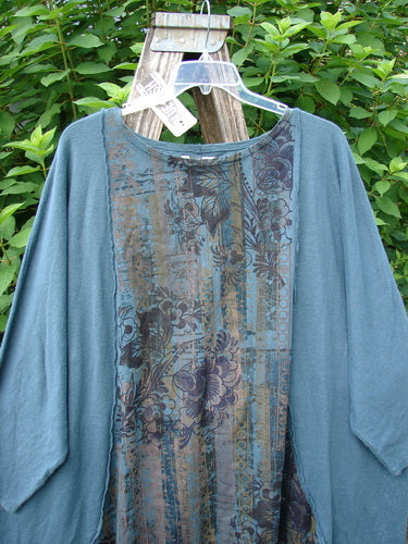 Barclay NWT Cotton Hemp Exterior Stitch Hi Low Tunic Botanical Hypnea Teal OSFA displayed on a plastic hanger, showcasing its dolman sleeves, generous shape, and exterior curvy stitchery against a neutral backdrop.