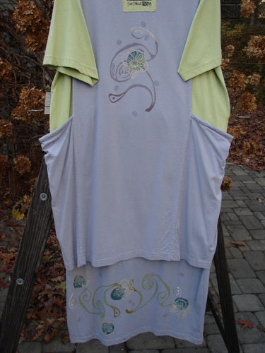 1997 Tunic Dress with Curly Garden Paint, Dawn Mellon, Size 1: A clothes rack with a close-up of a t-shirt featuring blue flowers, part of the vintage Blue Fish Clothing collection.
