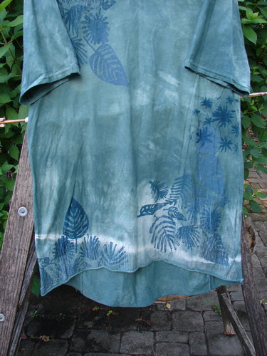 Barclay Tournesol Slim Tunic Beach Palm Mottled Green Earth OSFA showcasing a blue shirt with a leaf pattern, featuring a longer tunic length, drop shoulders, and loose three-quarter sleeves.