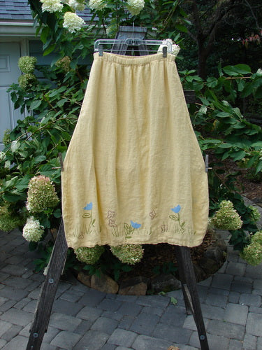 1999 Windy Day Skirt Tulip Buttercup Size 2 on a rack, showcasing its reverse bell shape with vertical pleats and a full elastic waistline, made of lightweight handkerchief linen adorned with floral patterns.