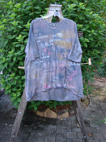 Barclay Tournesol Tunic Farm Land Mottled Grey Sky OSFA hanging on a clothesline, showcasing its drop shoulders, loose sleeves, rounded neckline, and varying hemline, embodying Bluefishfinder.com's vintage and creative style.