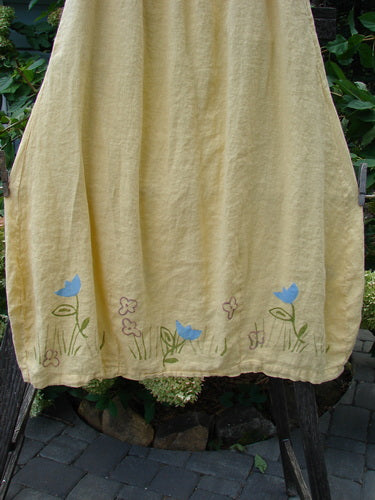 1999 Windy Day Skirt Tulip Buttercup Size 2: A yellow skirt with blue flower patterns, featuring a full elastic waistline, reverse bell shape, and vertical pleats, crafted from lightweight handkerchief linen.