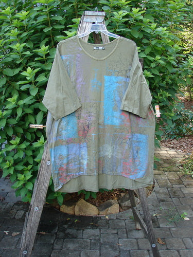 Barclay Tournesol Tunic Contour Forest Mottled Green Olive OSFA displayed on a wooden rack, showcasing its unique design with drop shoulders, loose sleeves, and varying hemline, embodying Bluefishfinder.com's vintage, expressive style.